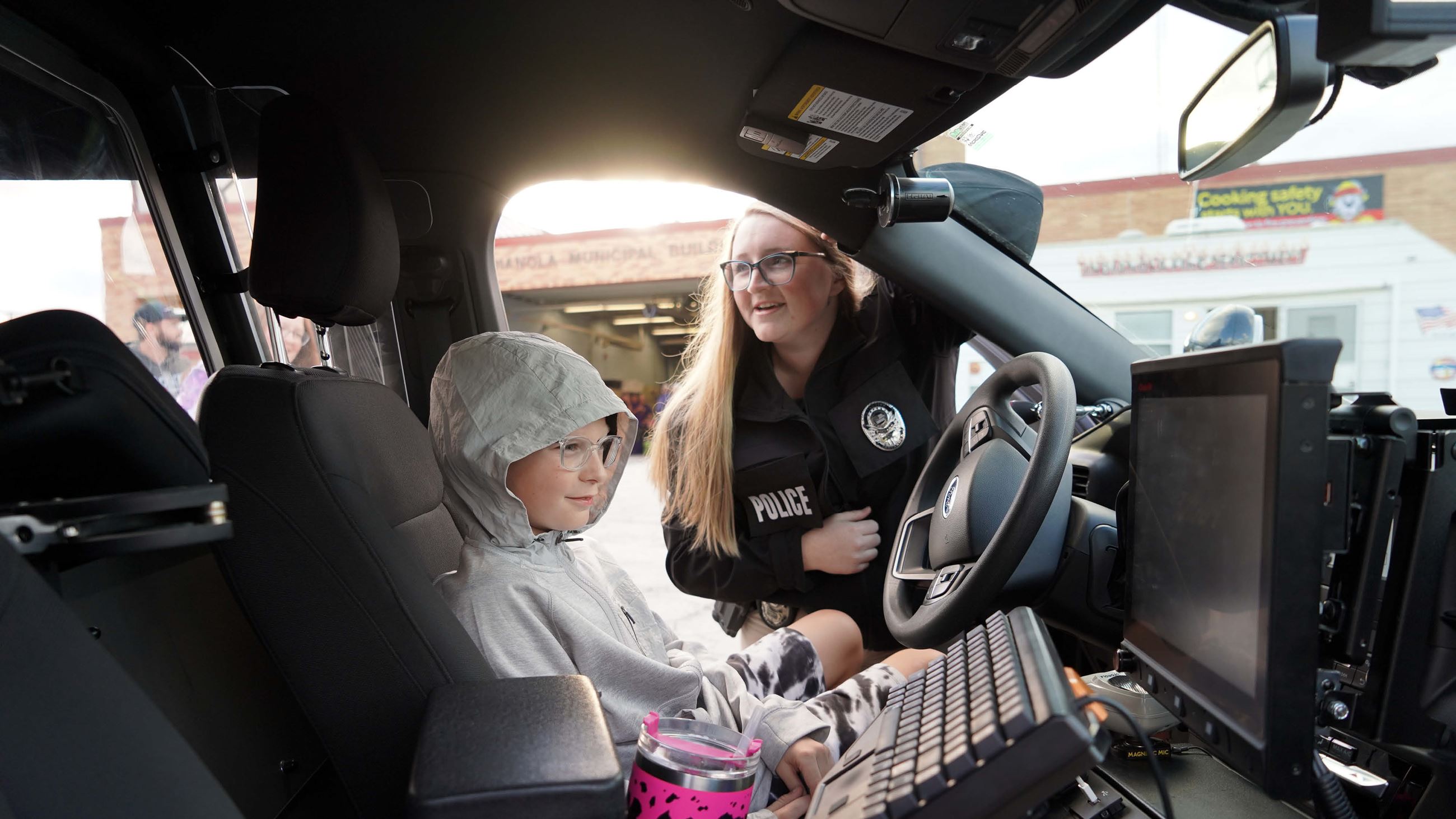 Indianola police officer Det. Nicole Brown and young resident inside a squad vehicle.