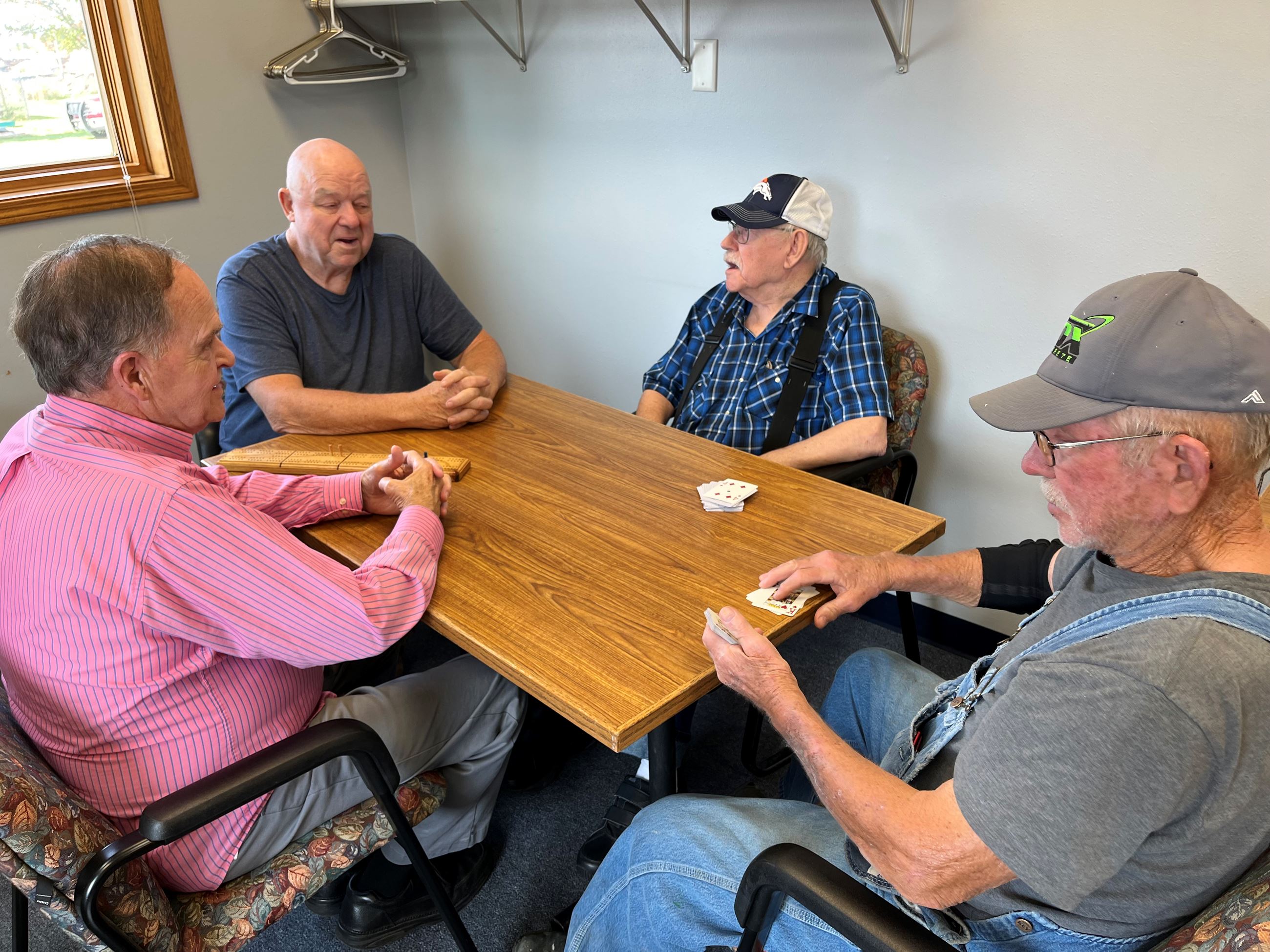 four men sitting at a table playing cribbage