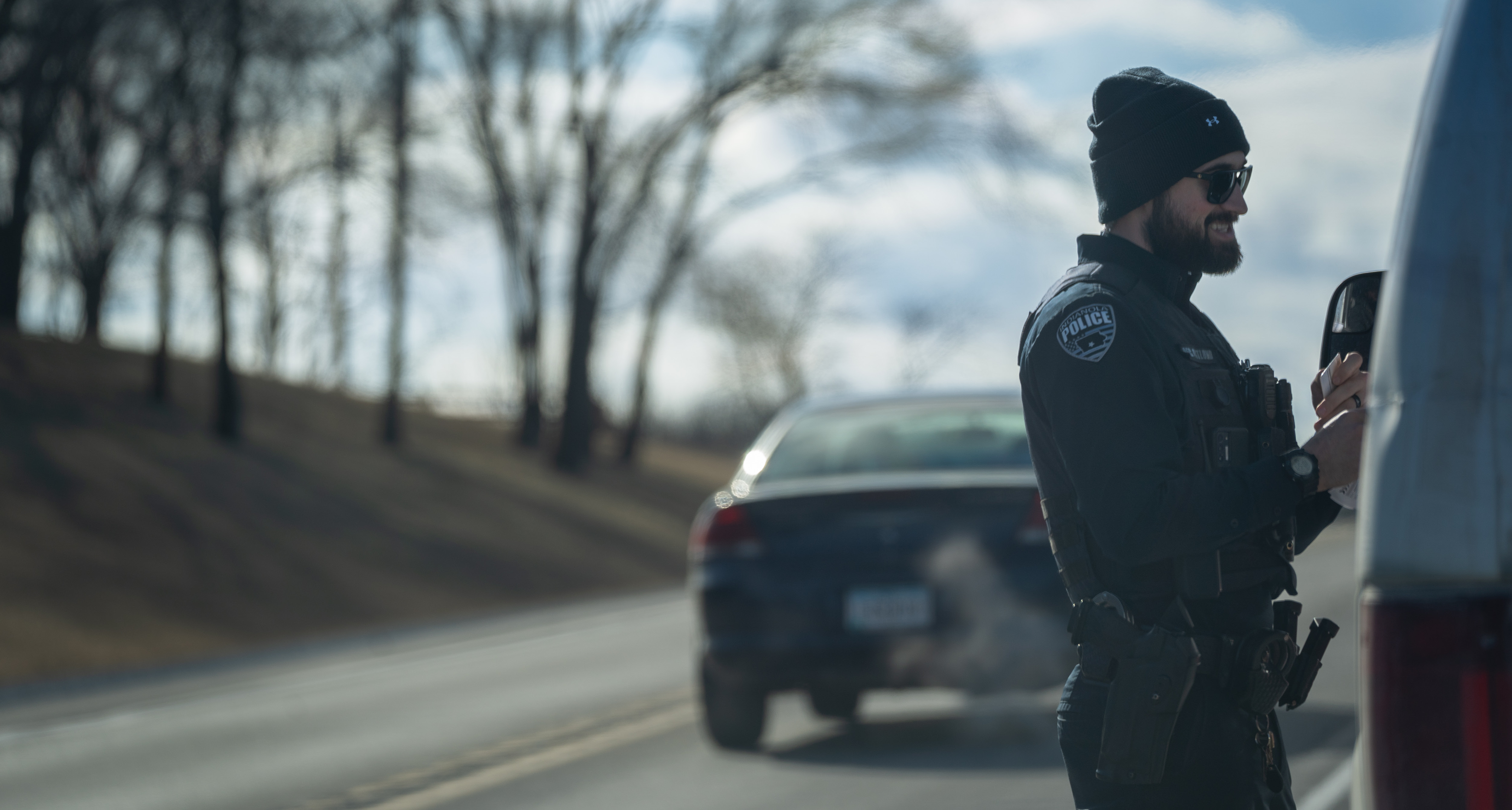 A police officer pulls over a vehicle on a highway during the daytime.