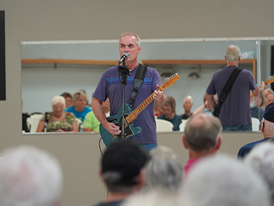 Man playing guitar and singing in front of a crowd of older adults.