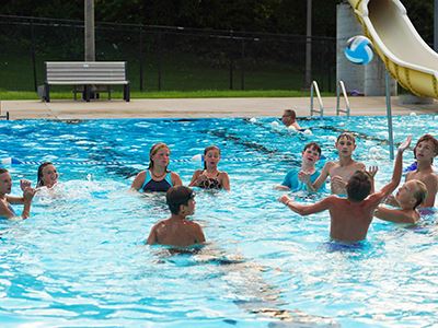 People playing keepaway with a ball at the pool
